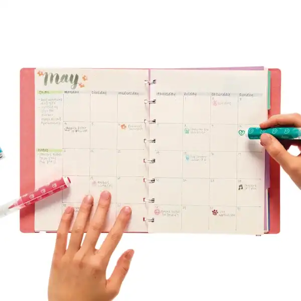 Person marking May calendar with colorful pens.