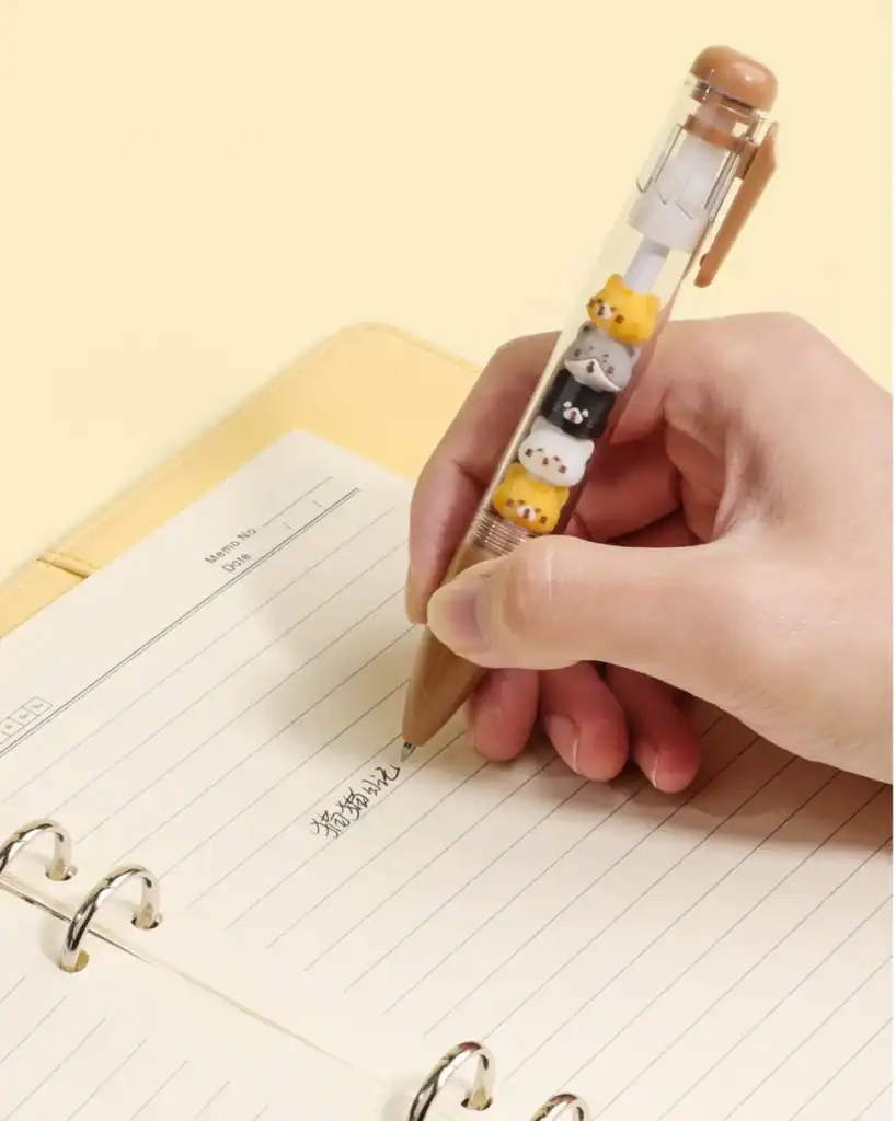 Handwriting with animal-themed pen in notebook.