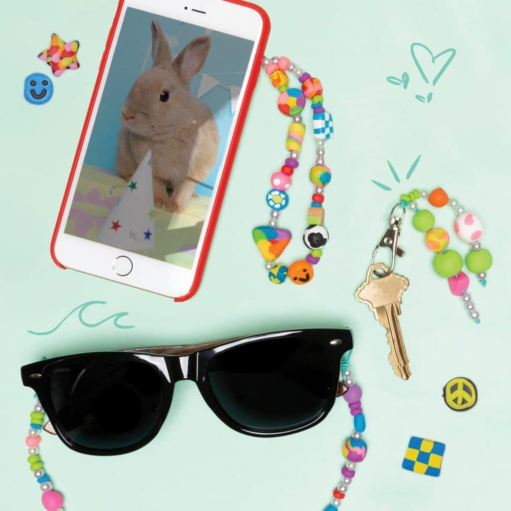 Sunglasses, smartphone with bunny, keys, and beads accessory.