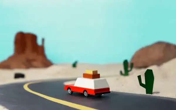 Toy car driving through desert landscape with cacti.