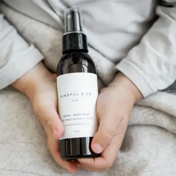 Child holding aromatherapy room spray bottle.