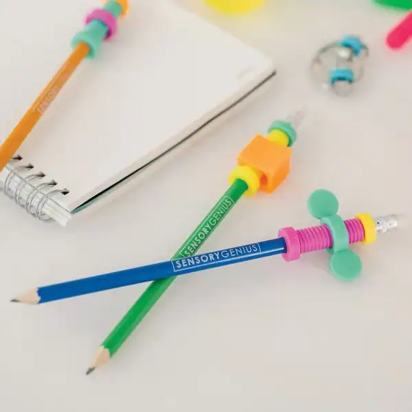 Colorful pencils with sensory fidget grips and notebook.