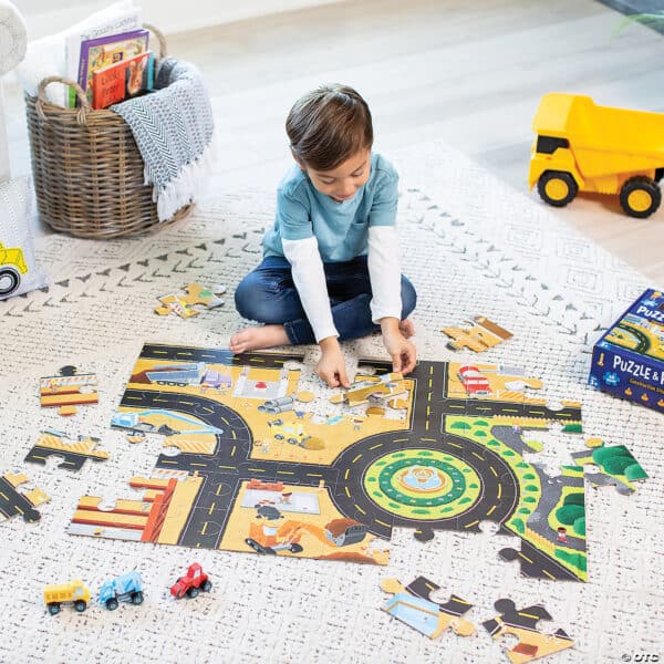 Child assembling road-themed puzzle on floor.