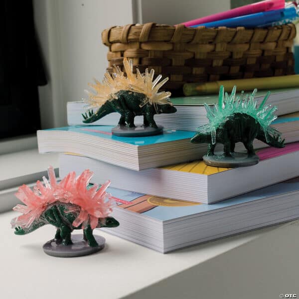 Crystal-covered dinosaur toys on stacked books.