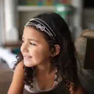 Smiling child wearing decorative headband indoors.