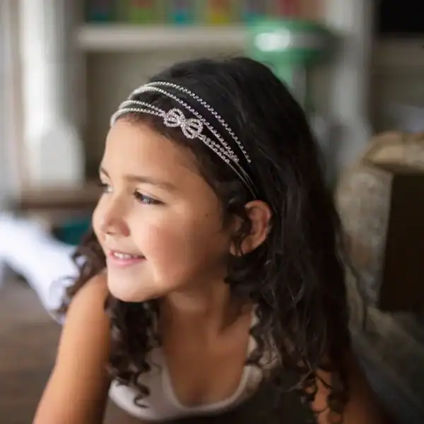 Smiling child wearing decorative headband indoors.