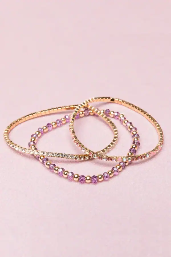 Gold and purple beaded bracelets on pink background.