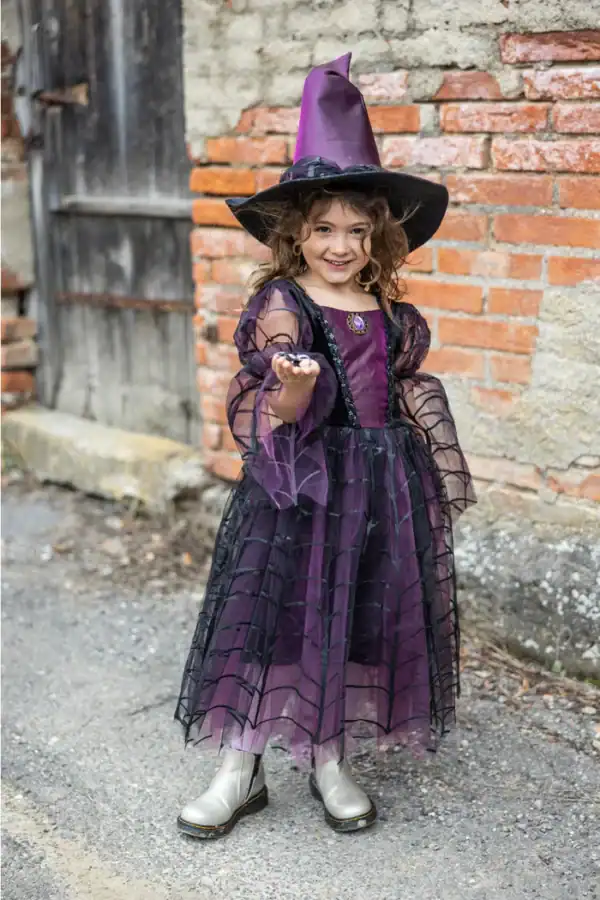Child in witch costume smiling outdoors