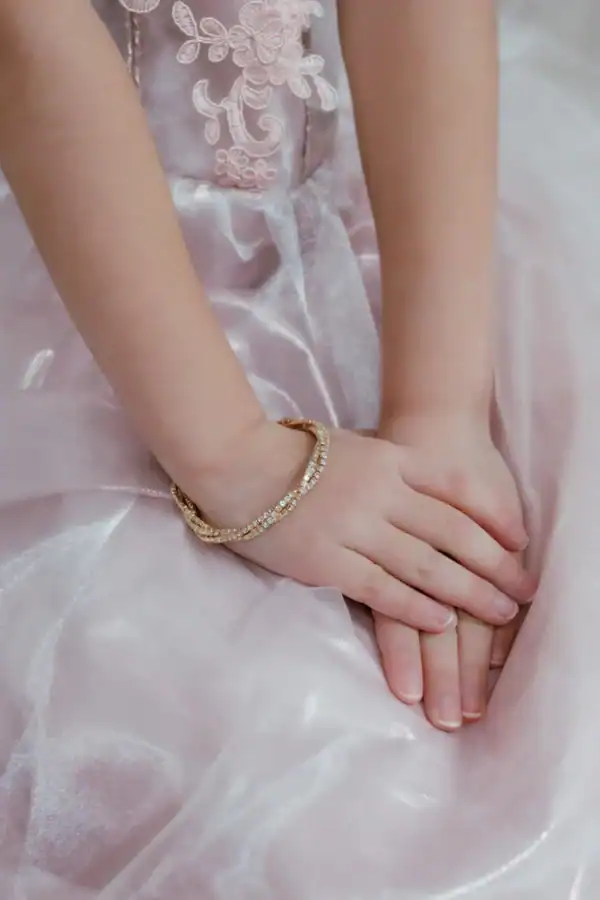 Child hands on pink dress with bracelet