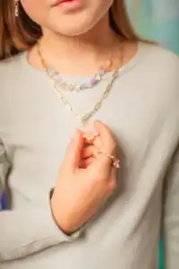 Child wearing colorful beaded necklace and rings.