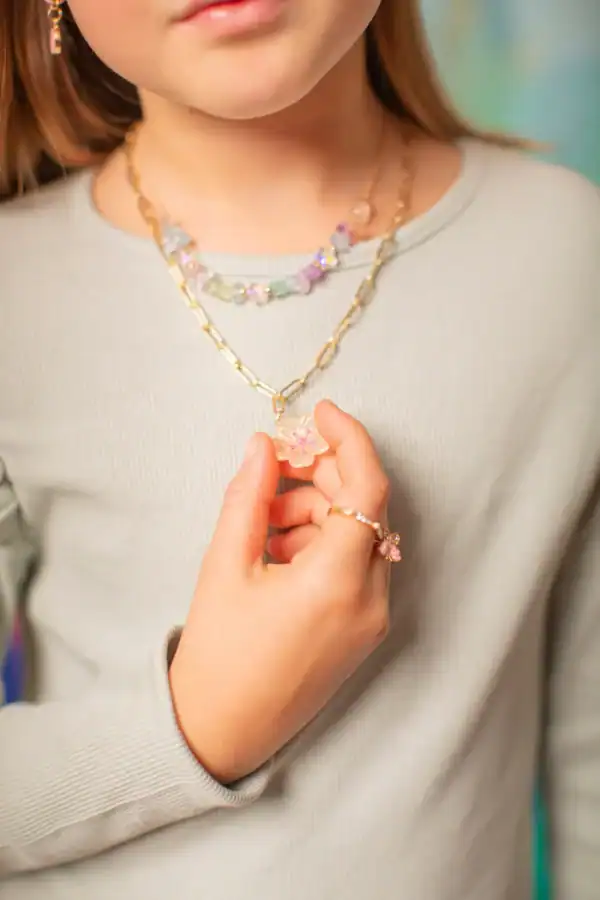 Child wearing colorful beaded necklace and rings.