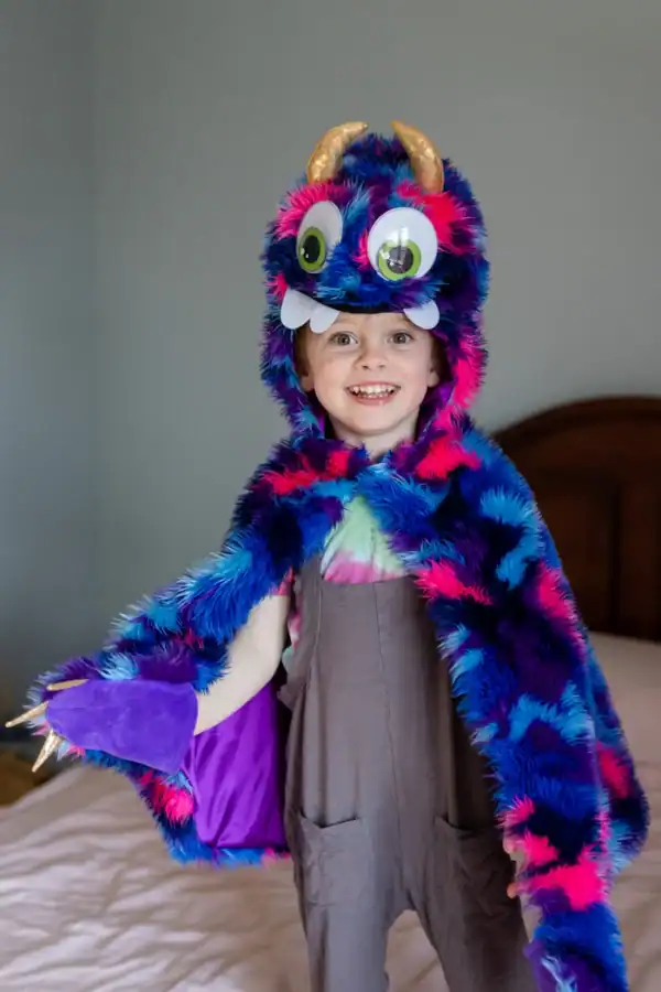 Child wearing colorful monster costume with big eyes.