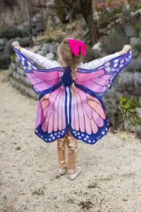 Girl wearing butterfly wings in outdoor setting.
