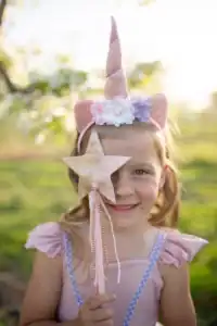 Girl in unicorn costume with star wand smiling
