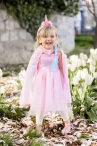 Child in unicorn costume among tulips outdoors