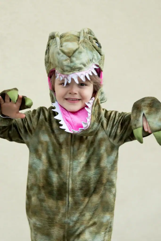 Child in dinosaur costume with pink interior.
