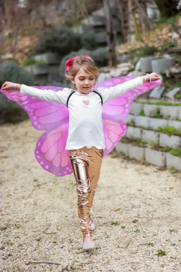 Child with pink butterfly wings and shiny leggings.