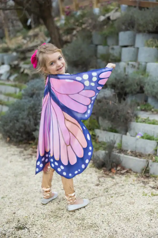 Child in butterfly wings costume in garden