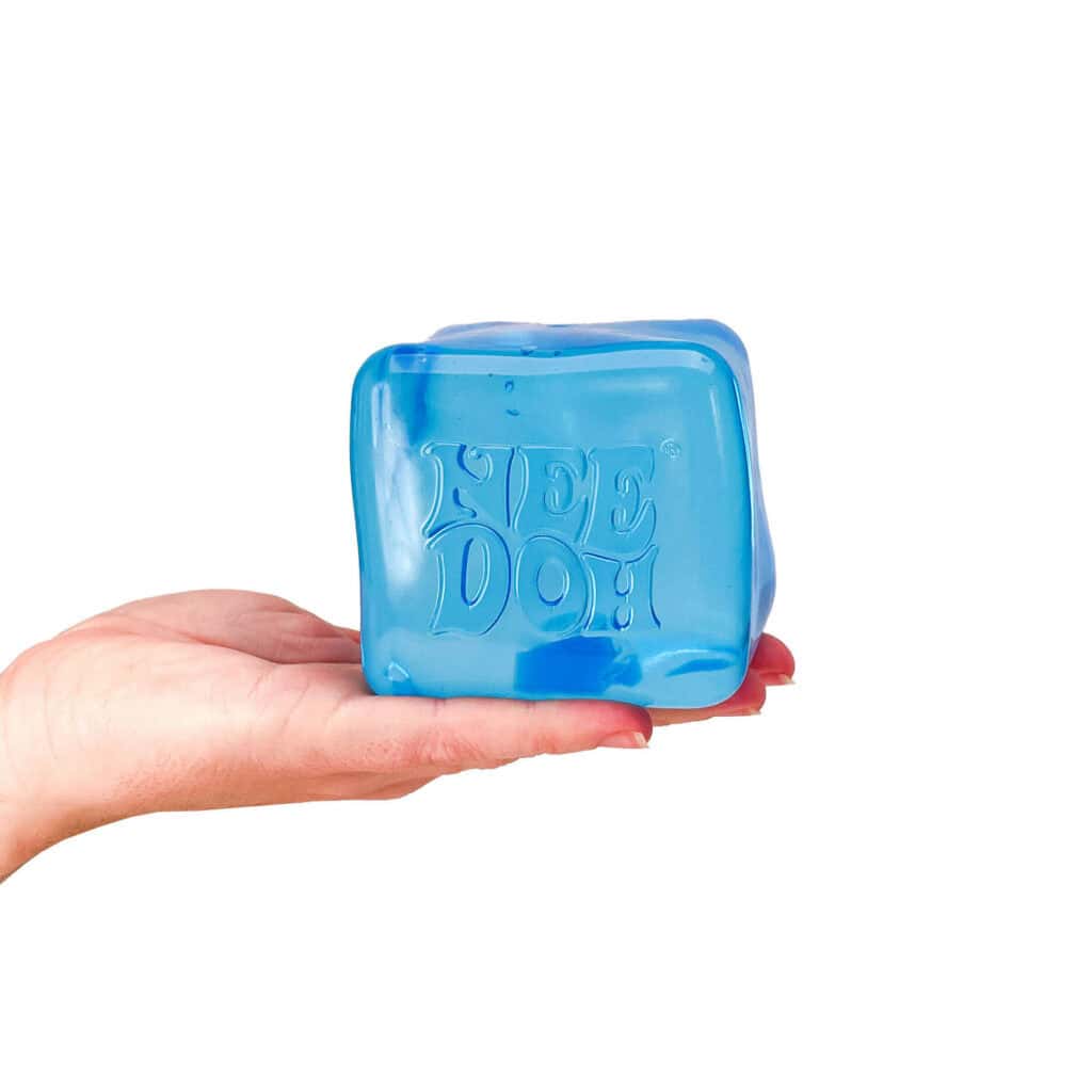 Hand holding blue Nee Doh stress ball cube.