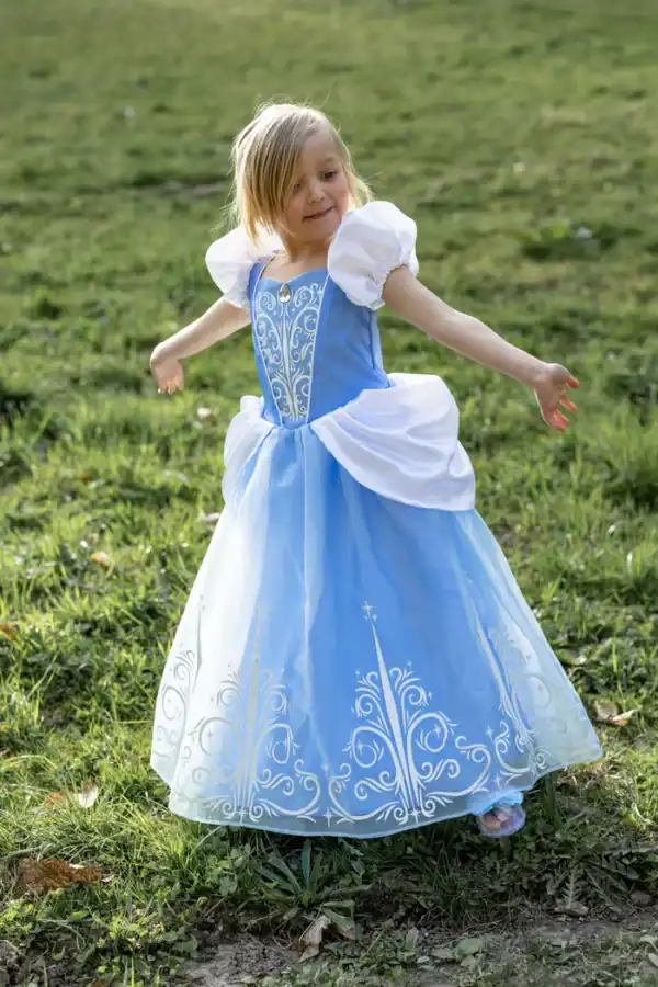 Child twirling in blue princess dress outdoors