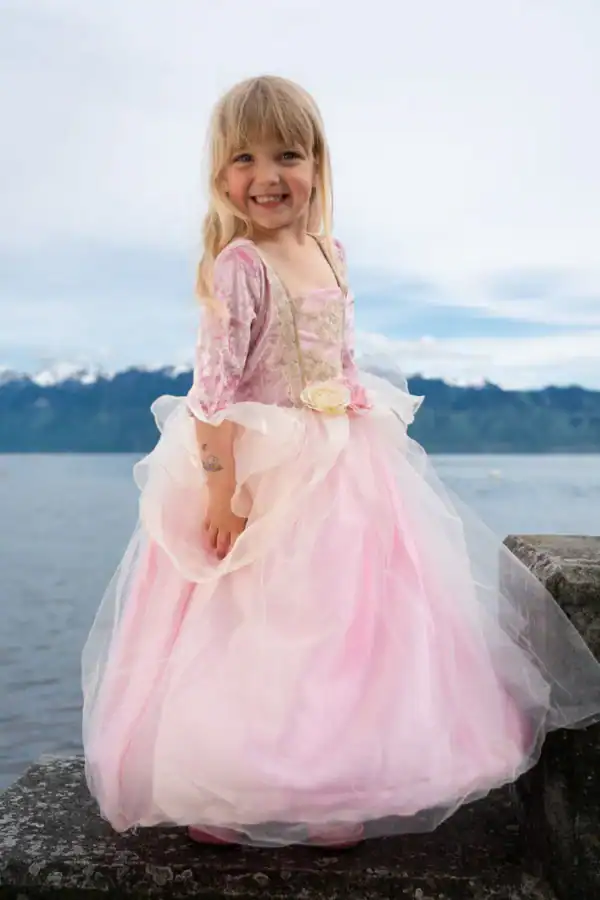 Smiling girl in pink dress by a lake