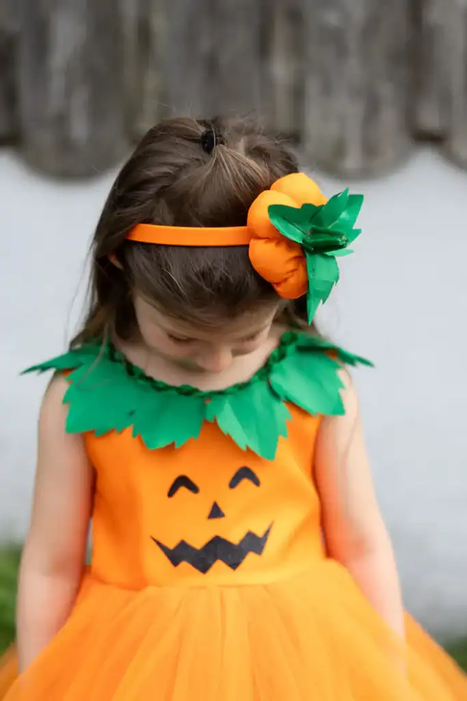 Child wearing pumpkin costume with headband