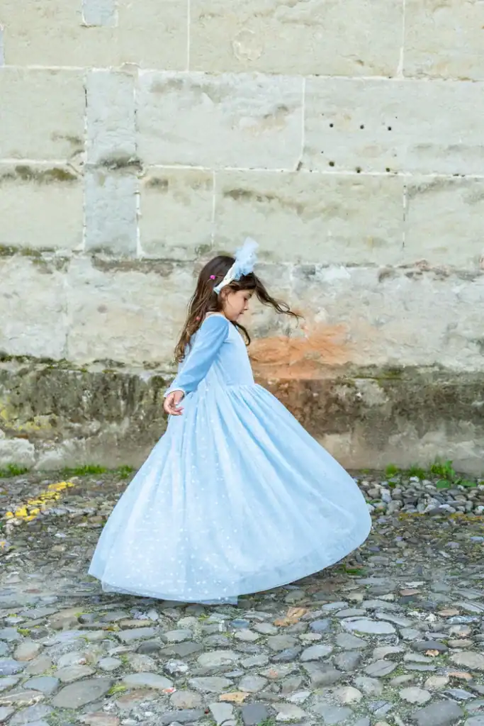 Girl twirling in a blue dress outside.