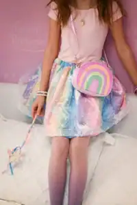 Child wearing rainbow dress and pink heart necklace.