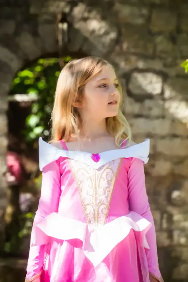 Child in pink princess costume at stone ruins.