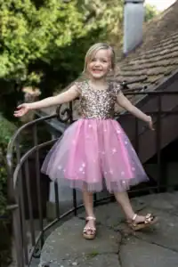 Smiling child in sparkly pink dress outdoors