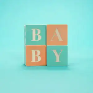 Wooden blocks spelling baby on colorful background.