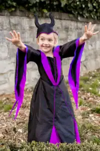Child wearing Maleficent costume posing outdoors.
