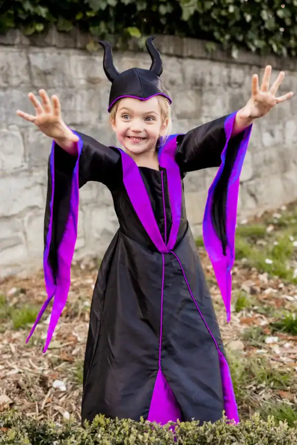 Child wearing Maleficent costume posing outdoors.