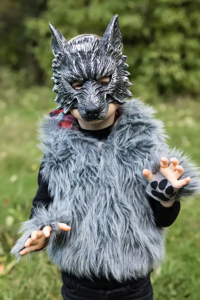 Child wearing wolf costume in a park.