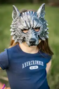 Child wearing wolf mask in blue shirt.