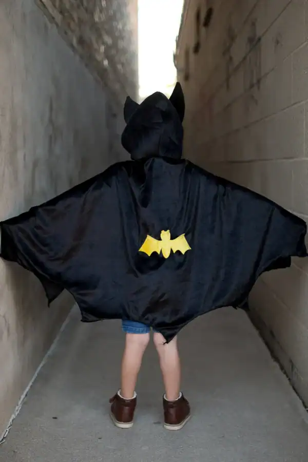Child wearing black bat costume in alleyway