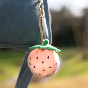 Plush strawberry keychain hanging from bag