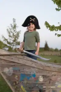 Child dressed as pirate on wooden ship.