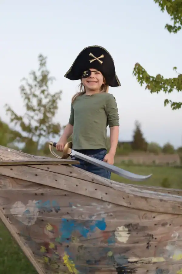 Child dressed as pirate on wooden ship.