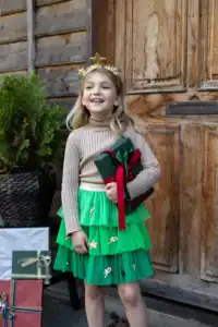 Child in festive dress holding a gift outdoors