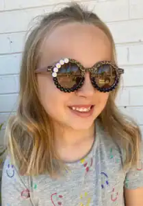 Child smiling wearing decorative sunglasses.