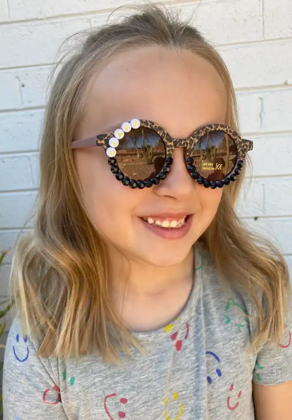 Child smiling wearing decorative sunglasses.