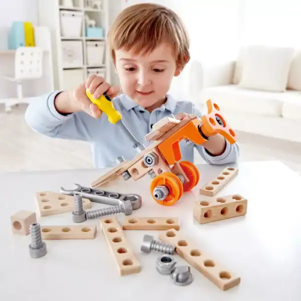 Child assembling wooden toy with screwdriver.