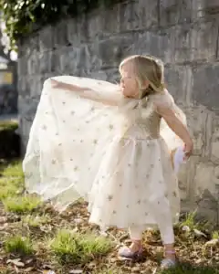 Child in sparkly dress with starry overlay outside.
