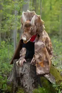 Person in dinosaur costume on tree stump
