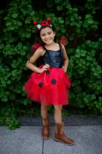 Child in ladybug costume smiles outdoors