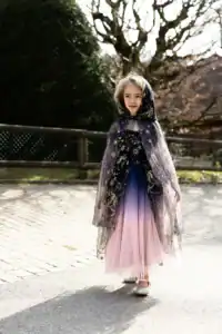 Girl in colorful dress and cape outdoors.
