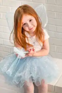 Child in fairy costume smiling at camera