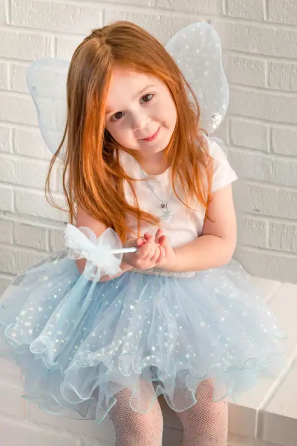 Child in fairy costume smiling at camera