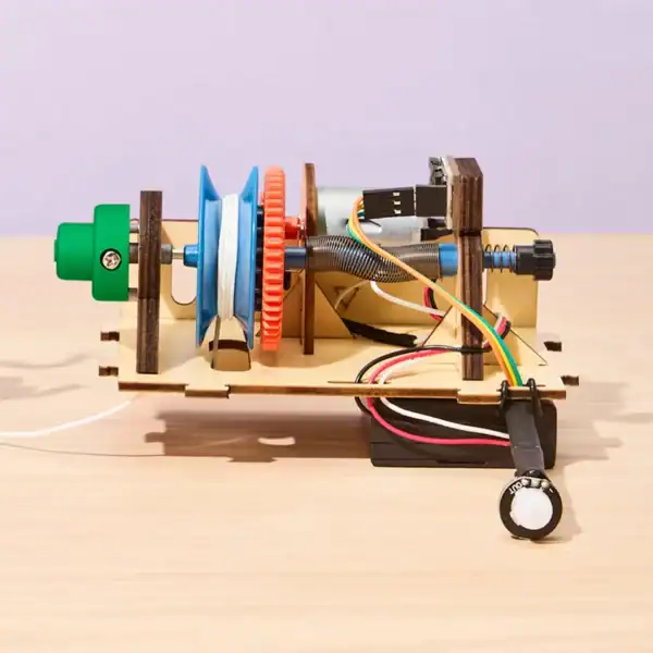 Colorful DIY motorized spool device on wooden table.